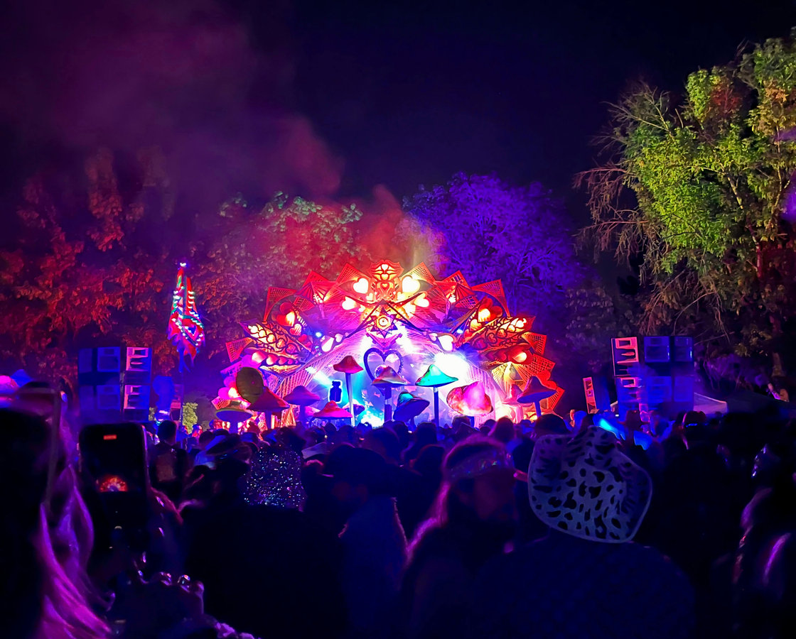 Crowd in front of a glowing, ornate festival stage at night